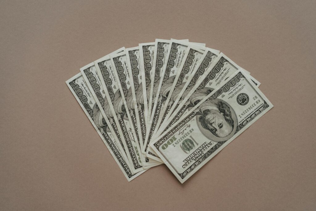 A neat arrangement of US dollar banknotes laid out in a fan shape on a brown surface.